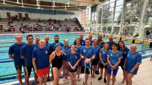 A group of swimmers posing for a picture in front of the pool